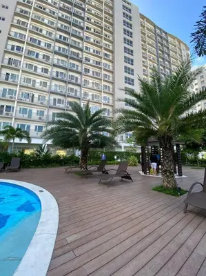 a large building with palm trees and a swimming pool at A Cozy 1 Bedroom Unit with a Parking at Tower 2 South Residences SM Southmall in Manila