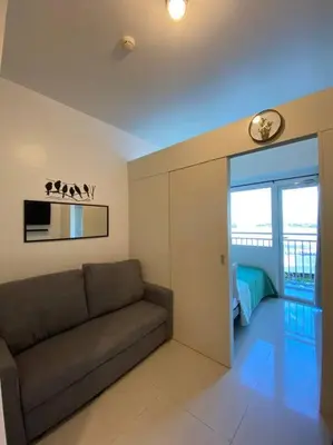 a living room with a couch and a microwave at A Cozy 1 Bedroom Unit with a Parking at Tower 2 South Residences SM Southmall in Manila
