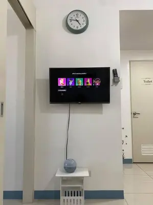 a clock on a wall with a tv on a wall at A Cozy 2 Bedroom Unit with a Parking at Tower 2 South Residences SM Southmall in Manila