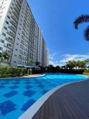 a large blue swimming pool in front of a building at A Cozy 2 Bedroom Unit with a Parking at Tower 2 South Residences SM Southmall in Manila