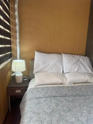 a bed with white pillows and a table with a lamp at FRD Condo Unit Tower A SoleMare Parksuites in Manila