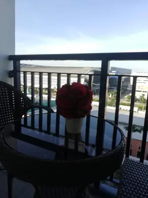 a vase of red roses sitting on a table on a balcony at Moa's Spot at Sea Residences in Manila