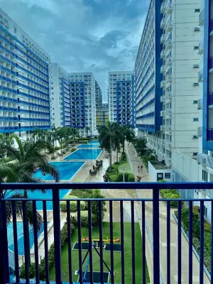 a balcony with a view of a pool and buildings at Azenith Staycation At Sea Residences Moa in Manila