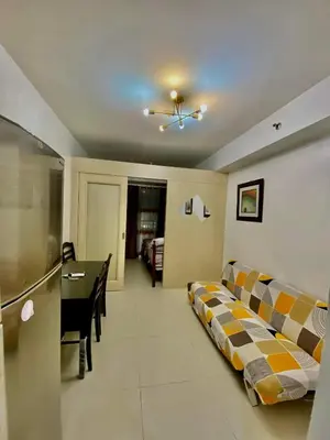 a room with two beds and a table in it at Azenith Staycation At Sea Residences Moa in Manila