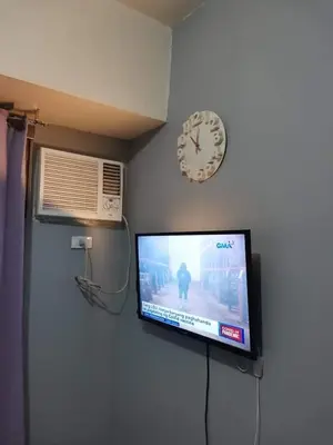 a tv on a wall with a clock on the wall at Mack's Awesome Place 11 with Netflix and FastUnliwifi in Manila
