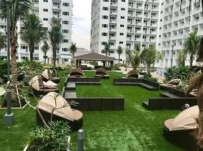 a park with benches and palm trees and buildings at SHELL RESIDENCE c5, shortwalk MALL OF ASIA near Airport in Manila