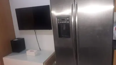 a stainless steel refrigerator with a television on a counter at SHELL RESIDENCE c5, shortwalk MALL OF ASIA near Airport in Manila