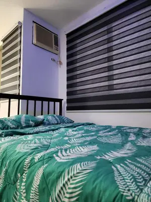 a bedroom with a bed with a green comforter and a window at Chichi's Snug Pad near Enchanted Kingdom and Nuvali in Santa Rosa
