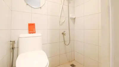 a white bathroom with a shower with a toilet at RedDoorz @ Malibu Room BF International Las Pinas in Manila