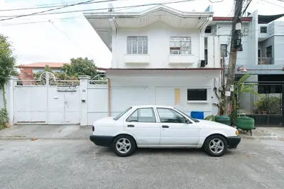a white car parked in front of a house at RedDoorz @ Malibu Room BF International Las Pinas in Manila