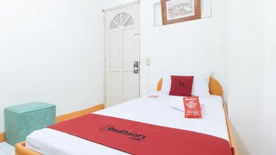 a bed in a room with a red blanket on it at RedDoorz @ Malibu Room BF International Las Pinas in Manila