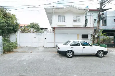 a white car parked in front of a white house at RedDoorz @ Malibu Room BF International Las Pinas in Manila