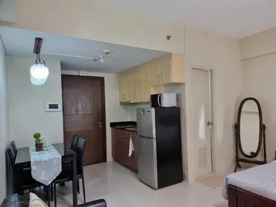 a kitchen with a refrigerator and a table with chairs at One Palm Tree Villas Condo Across NAIA Terminal 3 in Manila