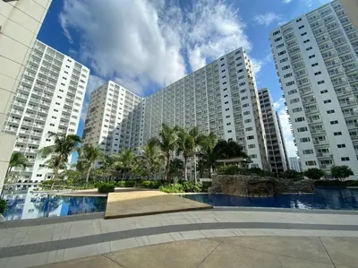 a large building with palm trees in front of it at Cozy Space at Shore Residences in Tower D in Manila