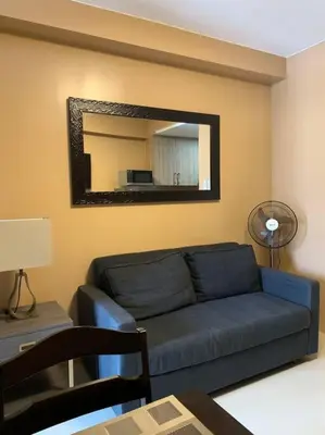a living room with a blue couch and a mirror at Cozy Space at Shore Residences in Tower D in Manila