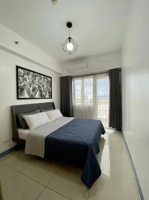 a bedroom with a large bed with a blue blanket at A Cozy 2 Bedroom Unit with a Parking at South Residences SM Southmall in Manila