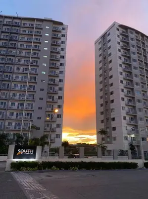 a large apartment building with a sunset in the background at A Cozy 2 Bedroom Unit with a Parking at South Residences SM Southmall in Manila