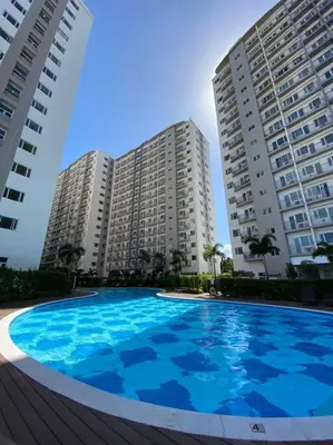 a large blue pool in front of two tall buildings at A Cozy 2 Bedroom Unit with a Parking at South Residences SM Southmall in Manila