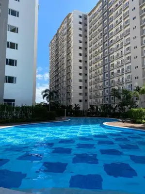 a large swimming pool in front of a large building at A Cozy 2 Bedroom Unit with a Parking at South Residences SM Southmall in Manila
