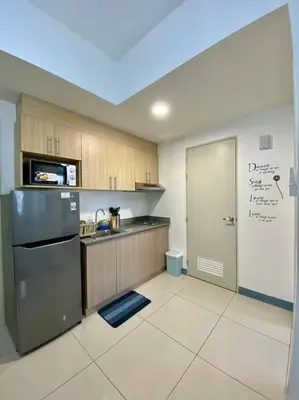 a kitchen with a refrigerator and a door in it at A Cozy 2 Bedroom Unit with a Parking at South Residences SM Southmall in Manila