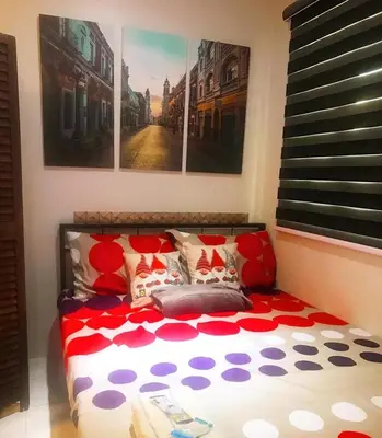 a bed with a red and white comforter in a room at Cozy Boo Bed and Breakfast near Enchanted Kingdom by Dynel in Santa Rosa
