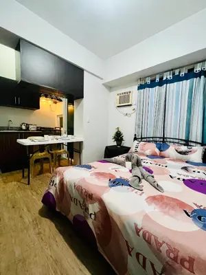 a bedroom with a bed and a table in a room at At Home Condo With Free Pool Access in Manila