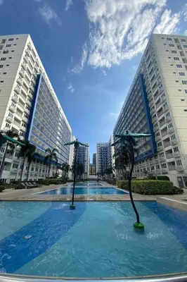 two tall buildings with a swimming pool in a city at Madison's Place at Sea MOA in Manila