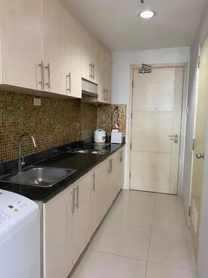a kitchen with white cabinets and a sink and a door at Madison's Place at Sea MOA in Manila