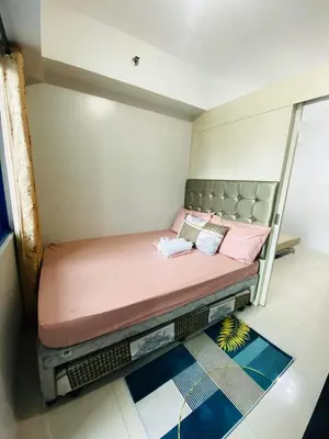 a small bedroom with a bed with pink pillows at Madison's Place at Sea MOA in Manila