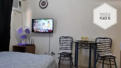 a bedroom with two stools and a tv on the wall at Mack's Awesome 15 with Netflix and FastUnliwifi in Manila