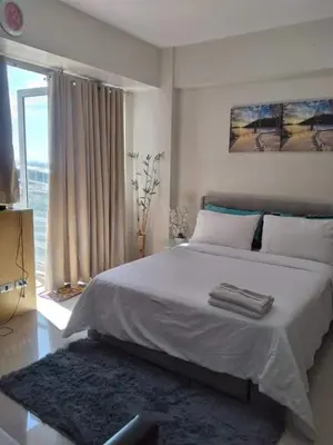 a bedroom with a large white bed and a window at One Palm Tree Villas NAIA TERMINAL 3 in Manila