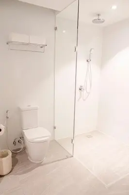 a white bathroom with a toilet and a glass shower at Lime Resort Manila in Manila