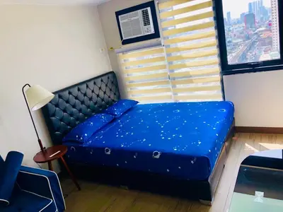 a blue bed in a room with a window at The Sentinel Residences in Manila