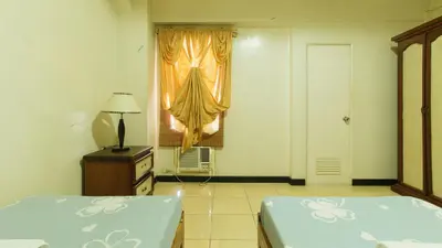 a bedroom with two twin beds and a window at Casa Micarosa Hotel and Residences by RedDoorz in Manila