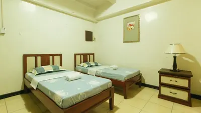 two beds in a room with a lamp and a table at Casa Micarosa Hotel and Residences by RedDoorz in Manila