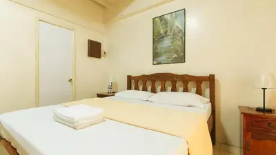 a bedroom with two beds and a picture on the wall at Casa Micarosa Hotel and Residences by RedDoorz in Manila