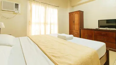 a bedroom with a bed and a dresser and a television at Casa Micarosa Hotel and Residences by RedDoorz in Manila