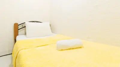 a bed with a yellow blanket and a pillow on it at JBs Transient House in General Trias