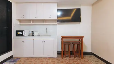 a kitchen with white cabinets and a table and chairs at Alamaris Resort RedPartner in Rizal