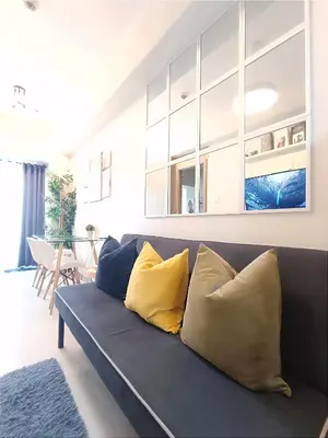 a living room with a blue couch with yellow pillows at SMDC Coast Residences near PICC World Trade Center MOA in Manila