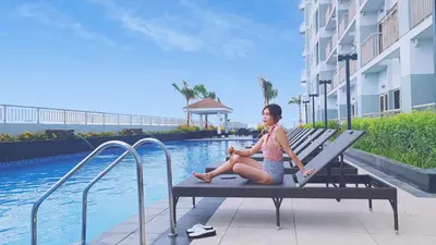a woman sitting on a bench next to a swimming pool at SMDC Coast Residences near PICC World Trade Center MOA in Manila