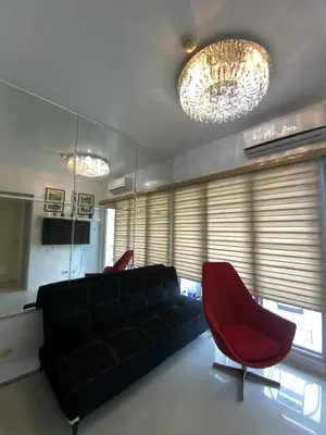 a living room with a black couch and a red chair at Sea Residences TowerE-F by EZStays in Manila