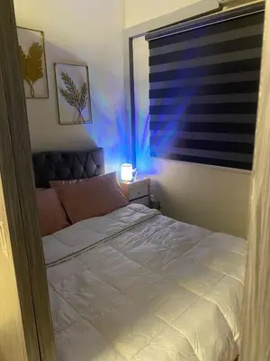 a bedroom with a bed and a window with blue lights at BayBreeze Haven Nest in Manila