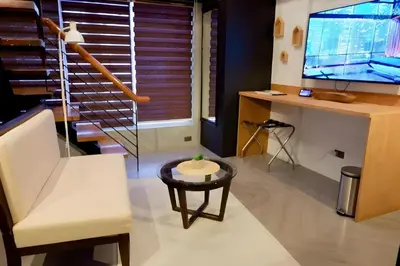 a living room with a chair and a table and a tv at Havitat Boutique Hotel in Manila