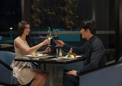 a man and woman sitting at a table with glasses of wine at Seda Bonifacio Global City Manila in Manila