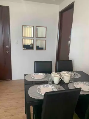 a dining room table with chairs and a black table with plates at Lovely Spacious Condo With Balcony in Manila