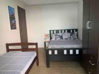 a bedroom with a bed and a chair in it at Lovely Spacious Condo With Balcony in Manila
