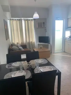 a living room with a table with plates on it at Lovely Spacious Condo With Balcony in Manila