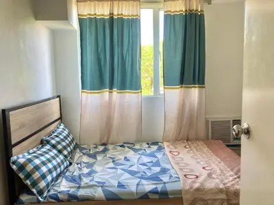 a bedroom with a bed and a window with curtains at Pacific Residences Condo Del Juana Near BGC Taguig in Manila