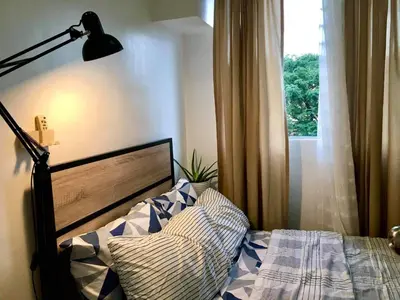 a bedroom with a bed with a lamp and a window at Pacific Residences Condo Del Juana Near BGC Taguig in Manila
